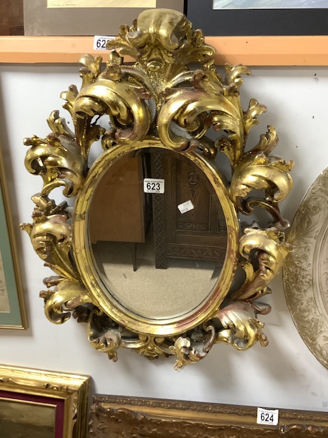 A ROCOCO STYLE GILT PAINTED COMPOSITE OVAL WALL MIRROR; 68X50 CMS.