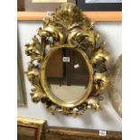 A ROCOCO STYLE GILT PAINTED COMPOSITE OVAL WALL MIRROR; 68X50 CMS.