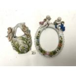 A CONTINENTAL PORCELAIN CHERUB MOUNTED OVAL PHOTO FRAME AND A PORCELAIN WALL POCKET.