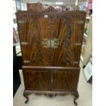 A FLAME MAHOGANY COCKTAIL CABINET FITTED WITH GLASS SHELVES AND COCKTAIL STICKS; 90X168X40 CMS.