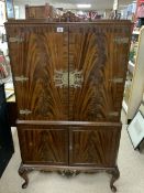 A FLAME MAHOGANY COCKTAIL CABINET FITTED WITH GLASS SHELVES AND COCKTAIL STICKS; 90X168X40 CMS.