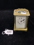 A BRASS CASED CARRIAGE CLOCK WITH WHITE ENAMEL DIAL; 12 CMS.
