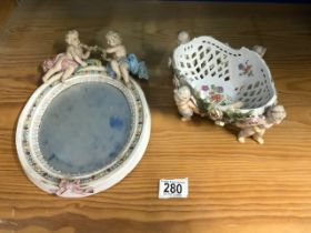 A CONTINENTAL PORCELAIN OVAL MIRROR WITH CHERUB MOUNTS AND PORCELAIN CHERUB SUPPORT BASKET.