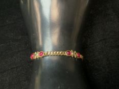 A 750 HALLMARKED GOLD BRACELET SET WITH FOUR CABACHON RUBIES; 10 GRAMS.