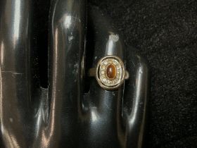 A YELLOW METAL RING SET WITH TIGERS EYE; SIZE L.