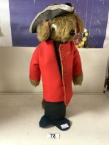 A SOFT TOY BEAR WEARING MILITARY GUARDSMAN COAT AND A TRICORN HAT, 40 CMS.