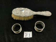 EMBOSSED SILVER BACK HAIR BRUSH AND TWO SILVER NAPKIN RINGS.