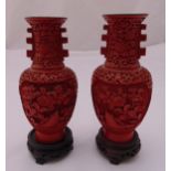 A pair of cinnabar lacquer vases carved with flowers and leaves on circular hardwood stands, 21cm (