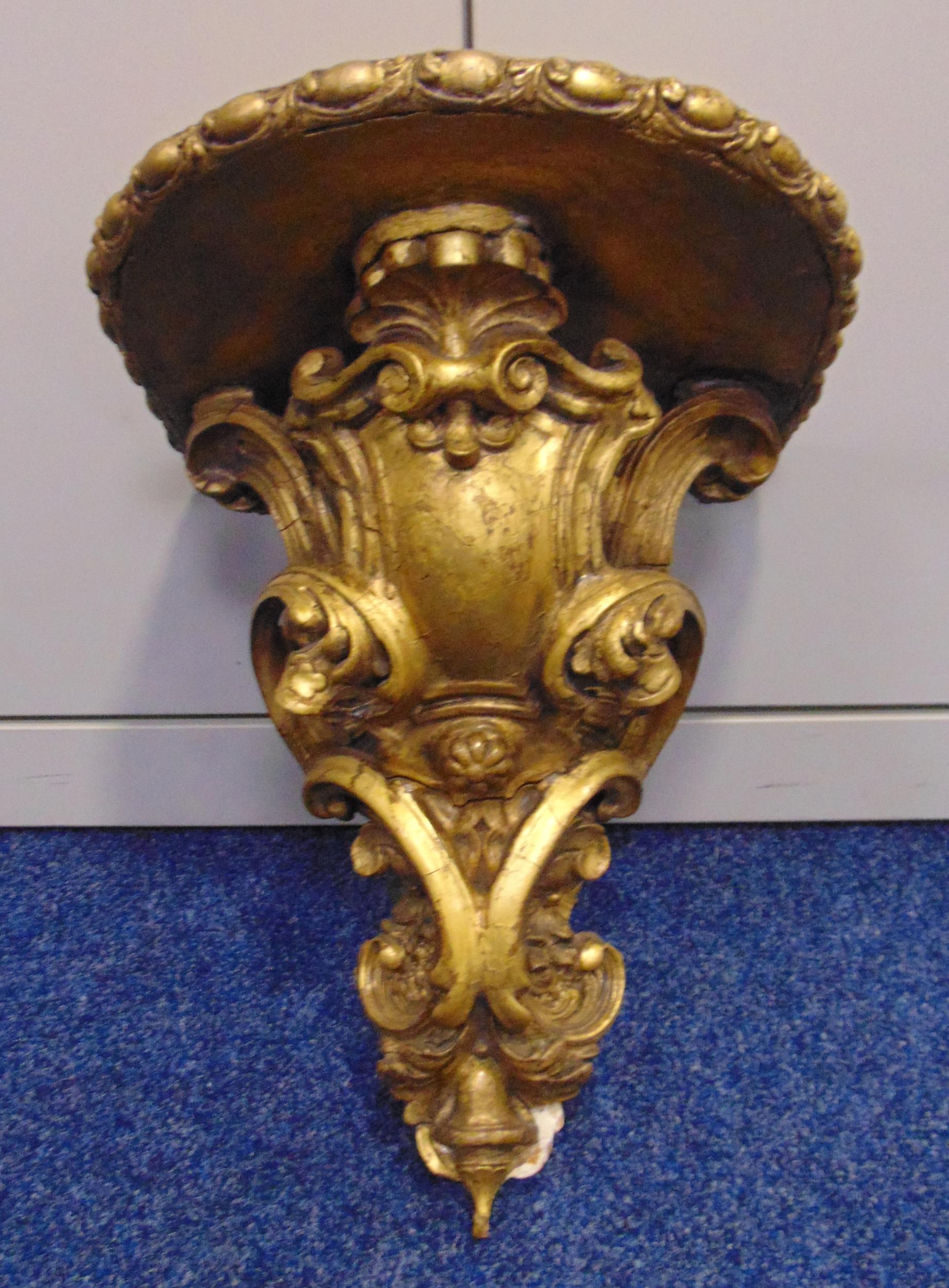 A 19th century continental carved gilded wall bracket with armorial shield and shell motifs, 40 x 33