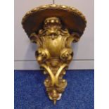 A 19th century continental carved gilded wall bracket with armorial shield and shell motifs, 40 x 33