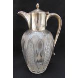 A cut glass and hallmarked silver claret jug of oval form, plain silver mounts, scroll handle and