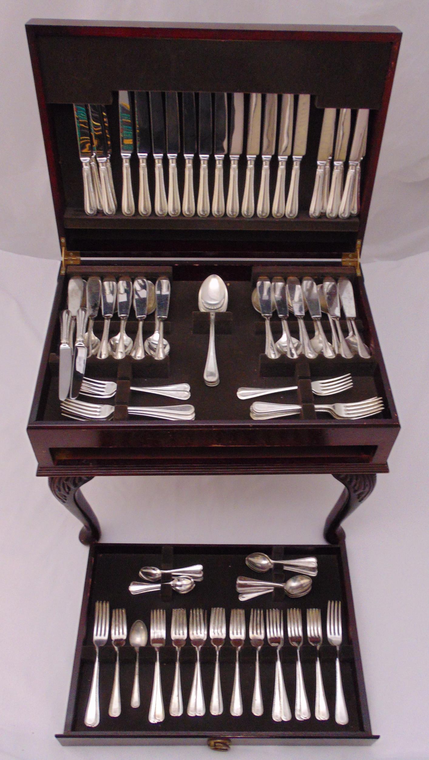 A canteen of silver plated flatware in mahogany free standing cabinet with tooled leather inset top