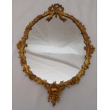 A gilded metal wall mirror, shaped oval with leaf and floral border, 57 x 40.5cm