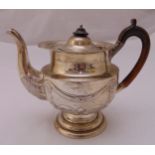 A hallmarked silver teapot, cylindrical chased with stylised leaves, swags and rosettes, with