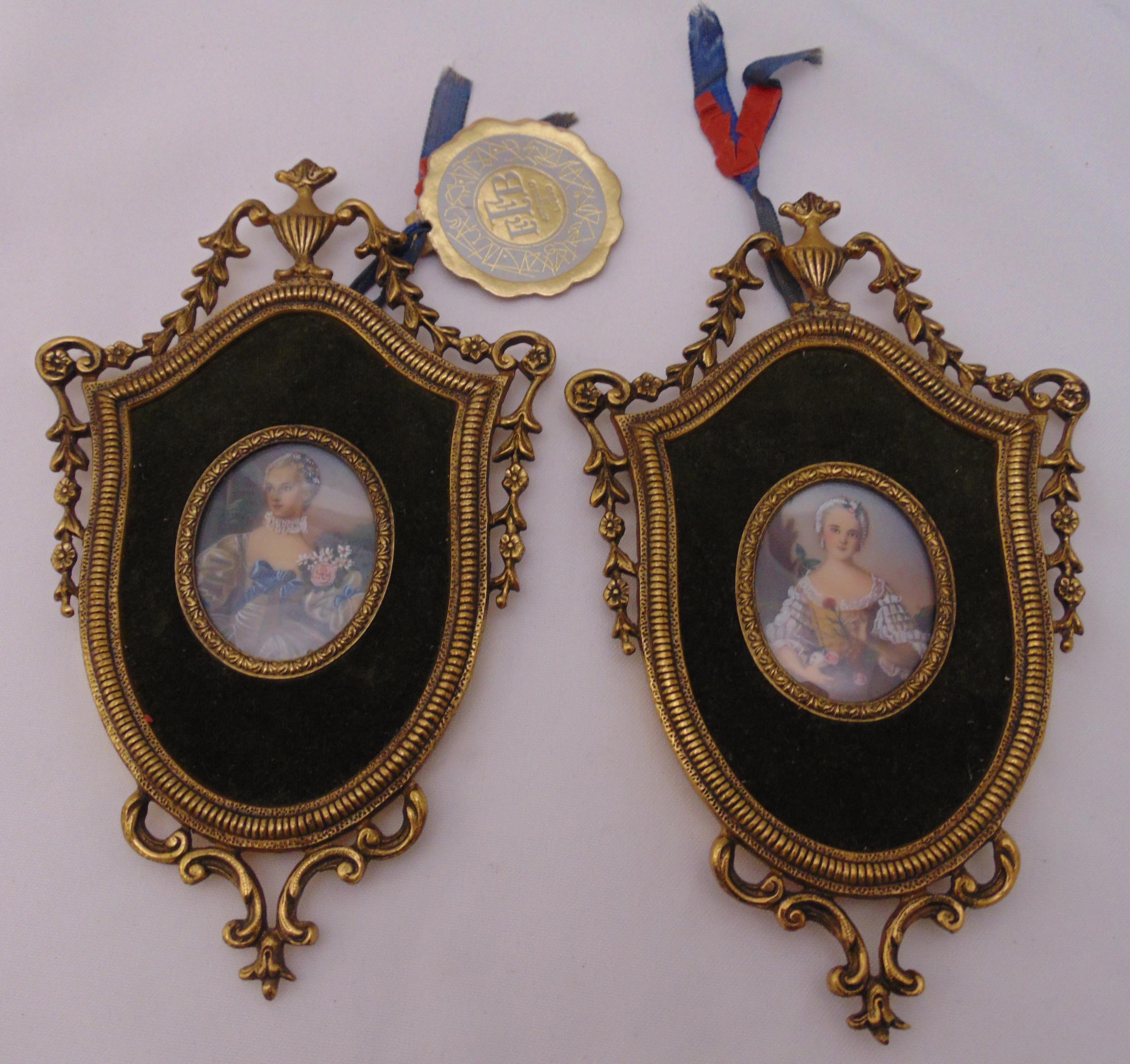 A pair of hand painted miniature portraits in gilded metal shield shaped frames