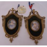 A pair of hand painted miniature portraits in gilded metal shield shaped frames
