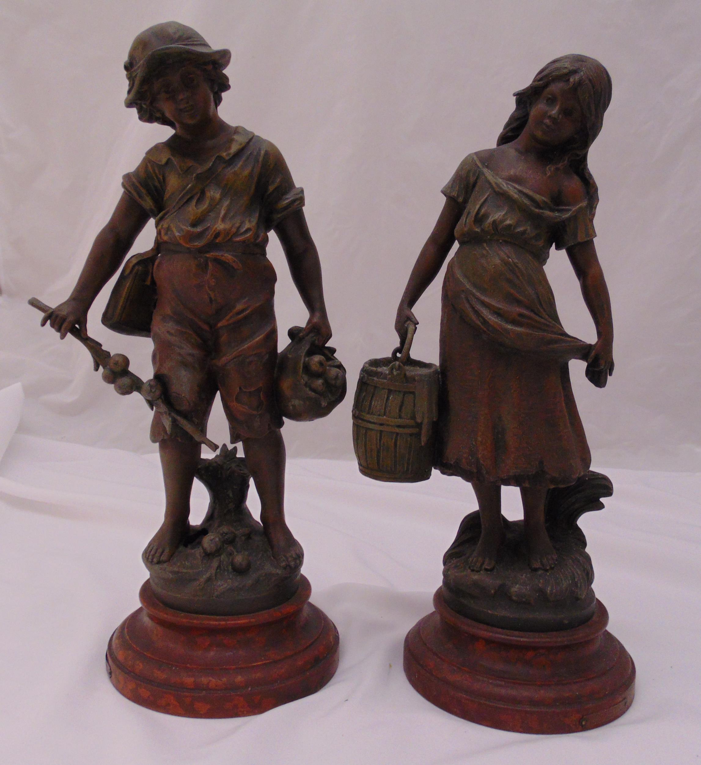 A pair of Victorian spelter figurines of a boy and a girl on raised circular composition plinths,