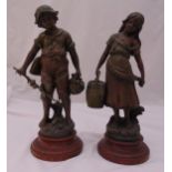 A pair of Victorian spelter figurines of a boy and a girl on raised circular composition plinths,