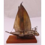 A silver plated model of a Dhow in full sail, mounted on a rectangular wooden plinth, 28cm (h)