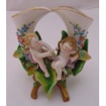 Meissen style figural group of putti sitting on leaves, crossed sword marks to the base, 20cm (h)