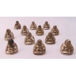 A set of twelve white metal place card holders in the form of Buddhas