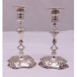 A pair of George II hallmarked silver table candlesticks, knopped stems on raised square bases