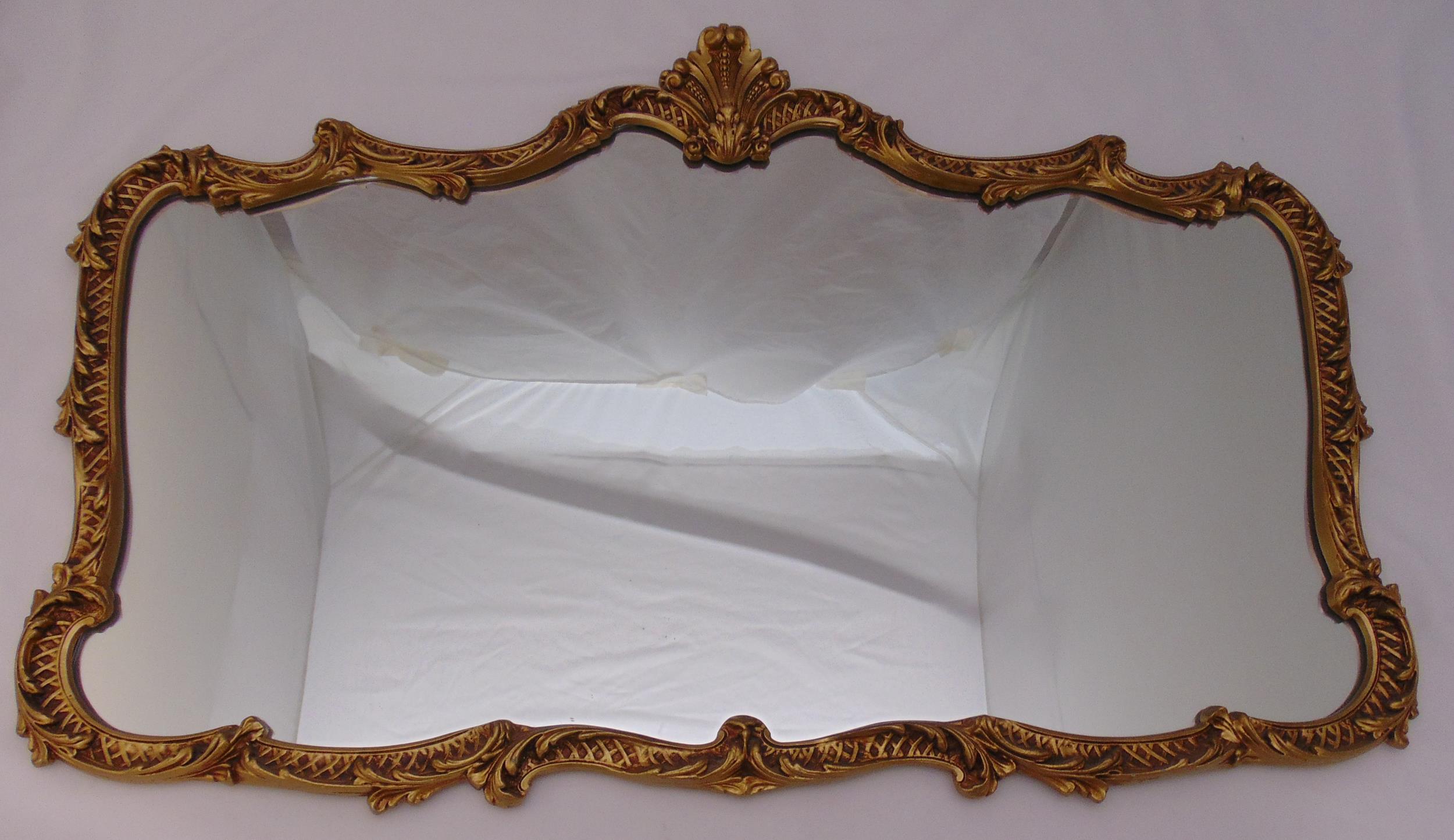 A gilded metal shaped rectangular wall mirror, 67 x 104cm