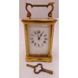 A gilt metal and glass carriage clock of customary form, white enamel dial with Roman numerals, to