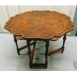 A walnut and mahogany drop flap, shaped circular tea table on turned cylindrical hinged supports