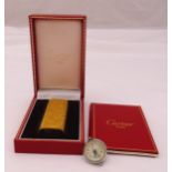 A Cartier cigarette lighter in original packaging and a pendant ball clock