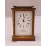 A brass carriage clock of customary form with enamel dial with Roman numerals, retailed by Searle of