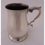 A hallmarked silver tankard with leaf capped double scroll handle on raised circular spreading base,