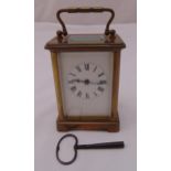 A brass carriage clock of customary form, white enamel dial with Roman numerals