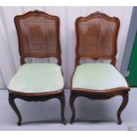 A pair of mahogany upholstered and caned occasional chairs on four scroll legs