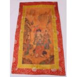 A Tibetan silk Tanka decorated with figures in a landscape within a red silk border, 67 x 111cm