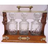 An oak Tantalus with three cut glass decanters with drop stoppers, 29.5 x 38cm
