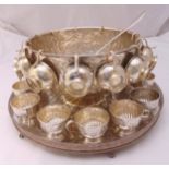 A silver plated punch bowl chased with flowers and leaves with twenty five cups and a punch ladle