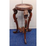 An oriental carved wooden plant stand with lion mask scroll legs supporting circular top with marble