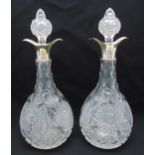 A pair of pear shaped cut glass decanters with hallmarked silver collars and drop stoppers, crest