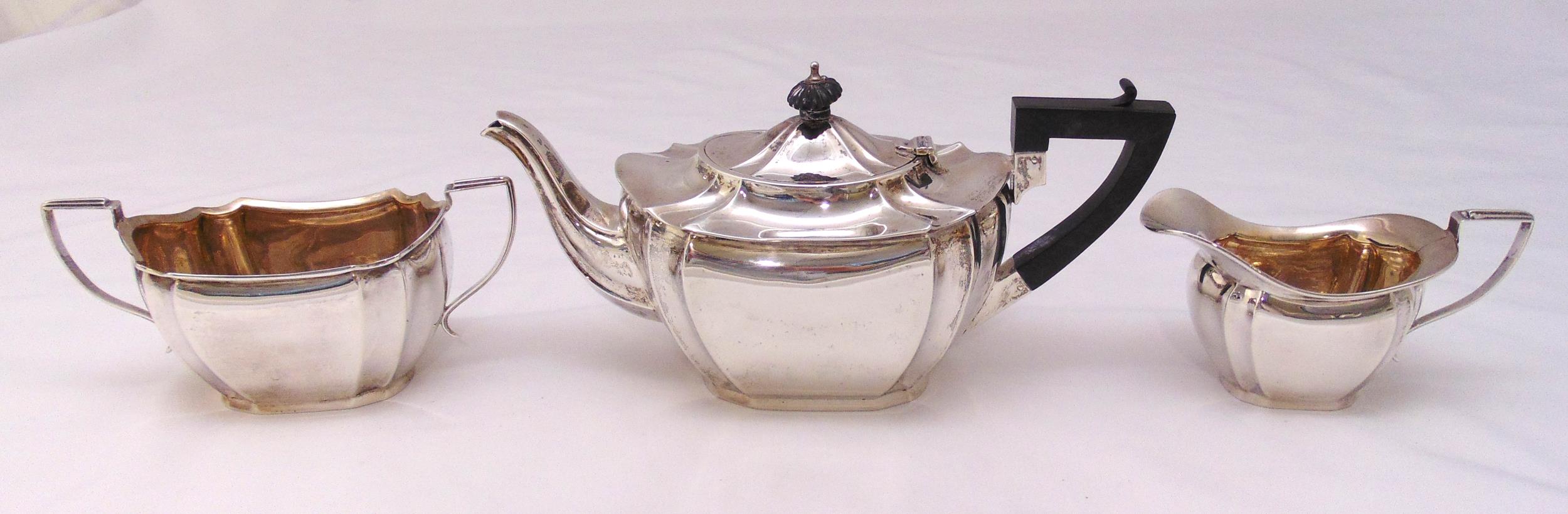 A hallmarked silver three piece teaset shaped oval with incuse sides and angled handles to include a