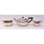 A hallmarked silver three piece teaset shaped oval with incuse sides and angled handles to include a