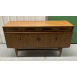 A mid 20th century rectangular teak sideboard with four cupboards and four drawers on raised