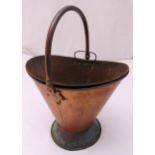 A 19th century beaten copper fireside coal bucket with hinged handle and insert on raised circular