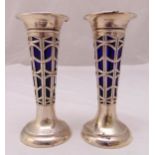 A pair of Victorian hallmarked silver pierced stem vases with detachable blue glass liners (liners