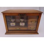 A late 19th century rectangular oak and glazed cabinet with three drawers with brass swing handles ,