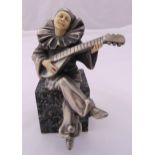 An Art Deco style silver plate and composition figurine of a jester playing a guitar on a raised