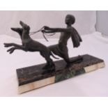 An Art Deco style figurine of a lady with two dogs on a leash all on rectangular marble base,