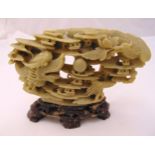 An oriental carved soapstone figurine of a stylised dragon on raised hardstone stand, 14 x 21cm