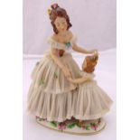 Dresden figurine of a lady and child dancing wearing matching lace dresses, mounted on an oval base,