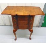 An early 20th century shaped rectangular three drawer walnut and mahogany set of drawers with drop